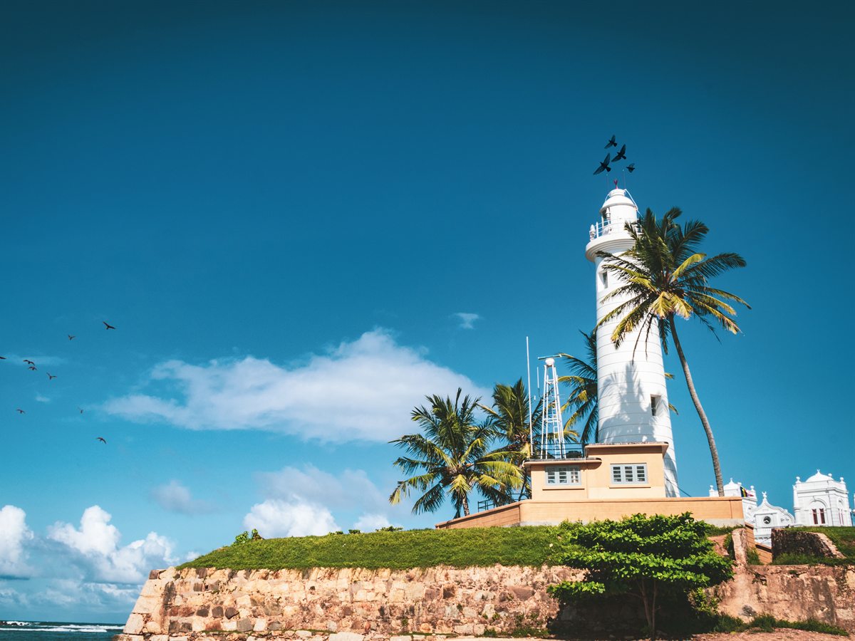 The white lighthouse and ramparts of Galle Dutch Fort against a blue sky