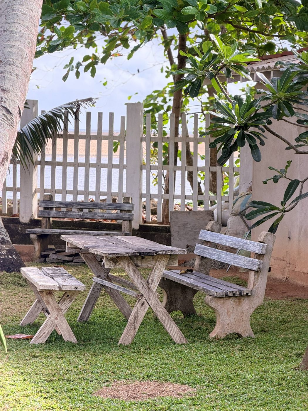 A rustic timber table by the white garden fence, the estuary beyond
