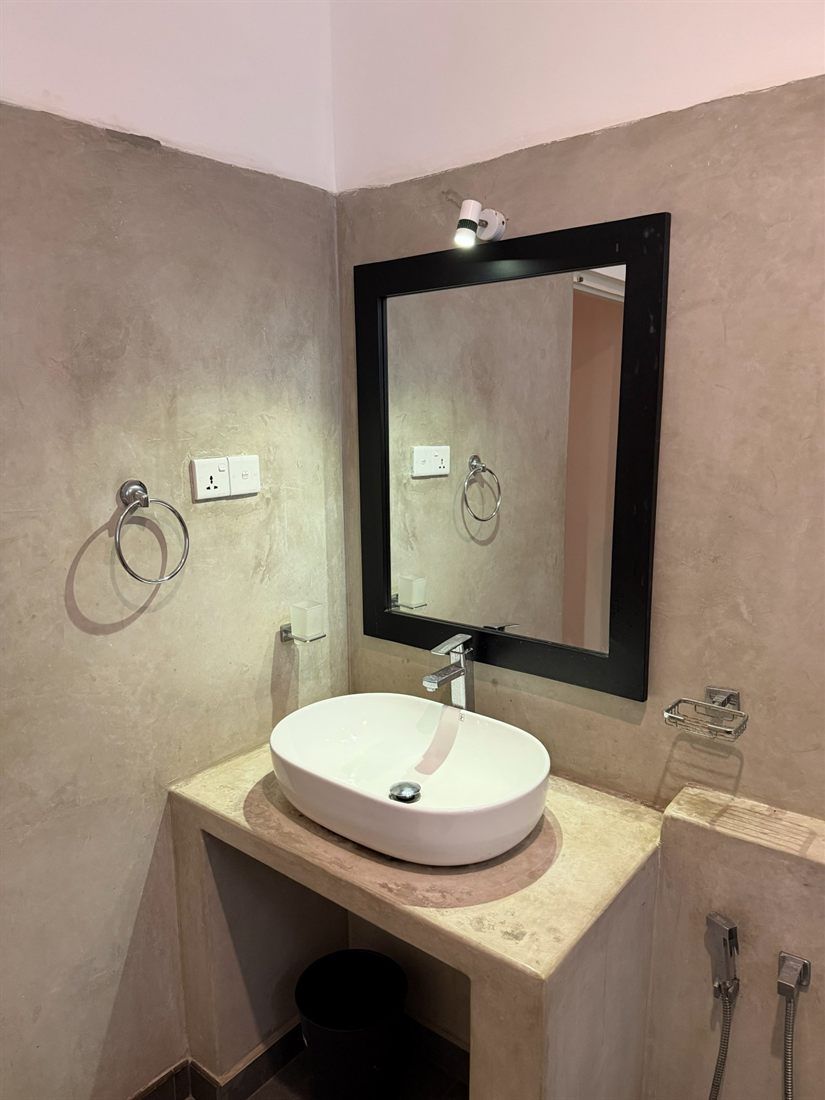 A polished-plaster bathroom with a vessel basin and a black-framed mirror