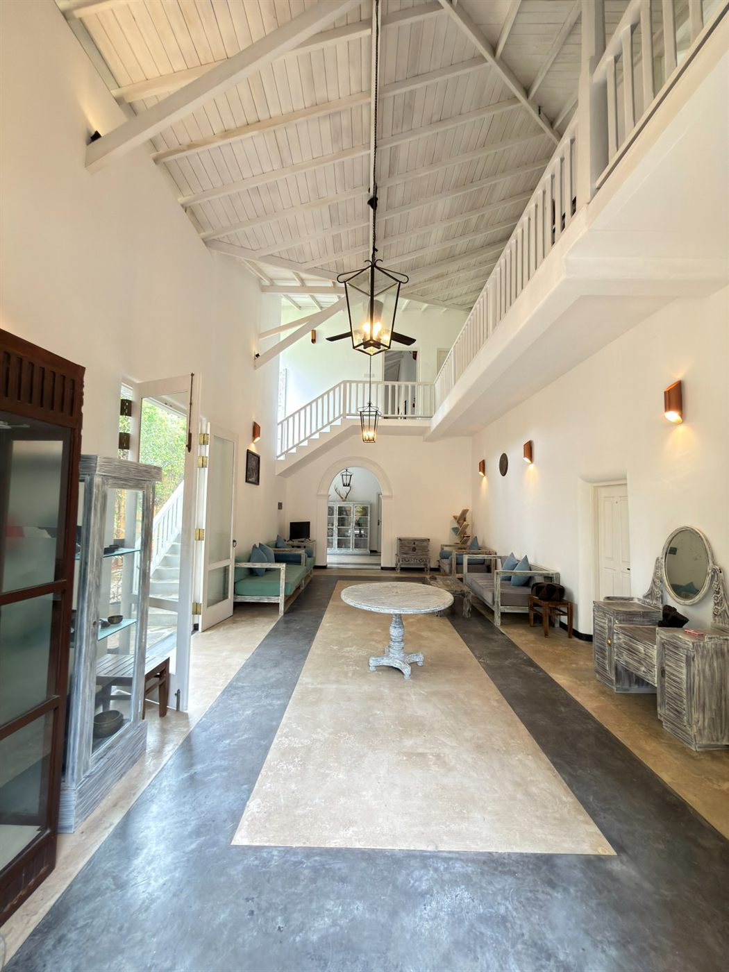 The double-height living hall with a white timber ceiling, mezzanine gallery and an arched doorway